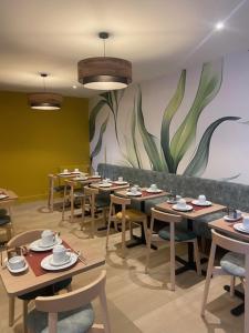 a restaurant with tables and chairs and a painting on the wall at The Originals Boutique, Hôtel de La Baie de Morlaix in Carantec +20 photos