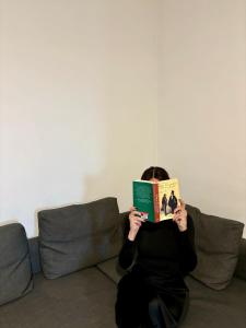 Una donna seduta su un divano a leggere un libro di Station Comfort House a Pagani