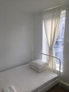 a white bed in a room with a window at Studio Manhattan Beach in Brooklyn