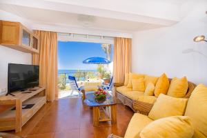 Una sala de estar con un sofá y un televisor. en Sunsuites Collection - Las Flores, en San Bartolomé