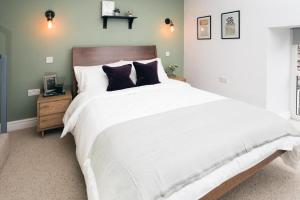 ein Schlafzimmer mit einem großen weißen Bett mit schwarzen Kissen in der Unterkunft Basin Cottage Retreat in Whaley Bridge