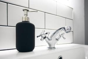 eine Seifenflasche auf einem Waschbecken neben einem Wasserhahn in der Unterkunft Basin Cottage Retreat in Whaley Bridge + 8 Fotos