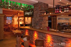 a bar in a restaurant with a stone wall at Berghotel Pointenhof in Sankt Johann in Tirol