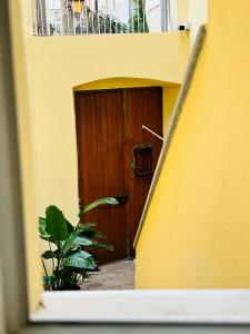 a wooden door in a yellow building with a plant at La Suite da Esther in Adrano