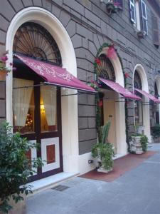 ein Gebäude mit zwei lila Sonnenschirmen außerhalb des Gebäudes in der Unterkunft Hotel Dina in Rom