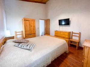 Un dormitorio con una cama y una cómoda con televisión. en Alojamiento Las Retamas, en El Bolsón 8 fotos más