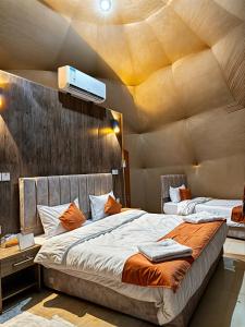 two beds in a room with a ceiling at Wadi Rum party luxury camp in Disah