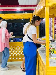 a woman preparing food at a food stand with a child at Wadi Rum party luxury camp in Disah +71 photos