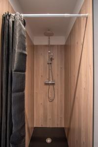 a shower in a bathroom with a wooden wall at Gite le palefrenier - 6 pers - 10 min Etretat in Gonneville-la-Mallet