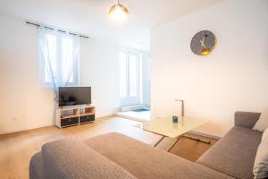 a living room with a couch and a clock on the wall at Gite le palefrenier - 6 pers - 10 min Etretat in Gonneville-la-Mallet