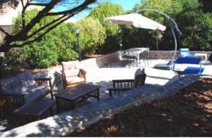 a group of chairs and an umbrella on a patio at Villetta Verde&Mare in Stintino