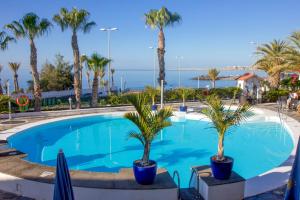 una piscina con palmeras y el océano en Sunsuites Collection - Las Flores, en San Bartolomé
