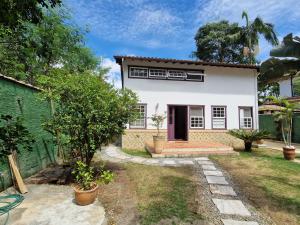 een wit huis met een rode deur en een tuin bij Casa Colonial Cabore in Paraty