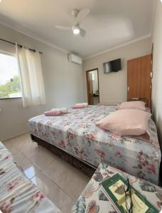 a bedroom with two beds with pink pillows at Suítes Nina e Malu in Santa Cruz Cabrália