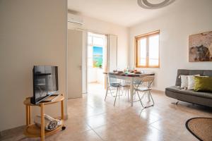 Una sala de estar con un televisor y una mesa con sillas. en Il gabbiano, en Otranto
