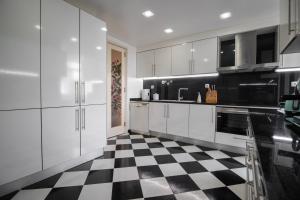 a kitchen with white cabinets and a checkered floor at Cocas House II - Almada in Almada