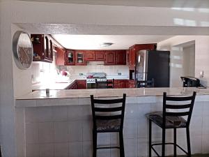 a kitchen with red cabinets and two bar chairs at GR20ACD Regina in Cuauhtémoc