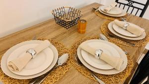 a wooden table with plates and utensils on it at Maison La Luciole LOUIS in Libreville