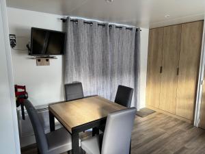 a dining room with a table and chairs and a television at Mobilhome camping le BOSC in Saint-Cyprien