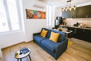 a living room with a blue couch and a kitchen at Le Sam Play in Mussidan