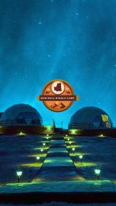 un cartello per un hotel su una spiaggia di notte di RUM ROZA BUBBLES lUXURY CAMP a Wadi Rum