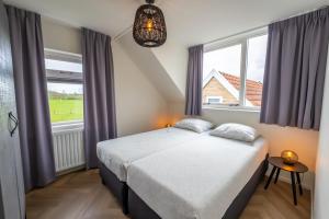 a bedroom with two beds and a large window at De Vrije wil in Buren