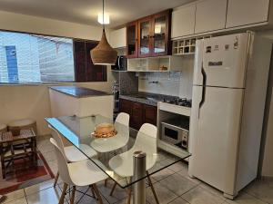 a kitchen with a glass table and a white refrigerator at Apto 201 l 300m da Praia l Wi-Fi, AC - Pirangi do Norte in Parnamirim