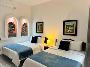 Una habitación de hotel con dos camas y cuadros en la pared. en Hotel Camino Maya, en Copan Ruinas