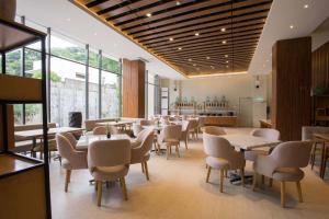 a dining room with tables and chairs and windows at Allstay Hotel Semarang Simpang Lima in Semarang