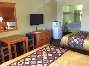 a hotel room with two beds and a desk and a television at Americas Best Value Inn Pryor in Pryor