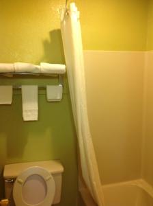 a bathroom with a toilet and a shower curtain at Americas Best Value Inn Pryor in Pryor