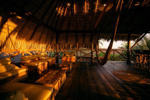 a room with couches and chairs in a straw hut at Secret Spot by Palapita Beach House in Puerto Escondido