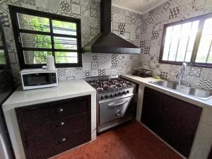 a kitchen with a stove and a sink and a microwave at La escondida in Ramallo