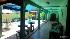 un patio con mesas y sillas y una piscina en Suítes Casa Verde, en Arraial do Cabo