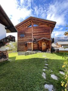 une cabane en rondins avec une cour herbeuse devant elle dans l'établissement Résidence Grenier De Koikoi - Chalet de standing : Grenier de Koikoi MAE-2404, à Notre-Dame-de-Bellecombe