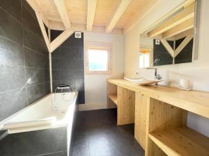 une salle de bains avec baignoire et lavabo dans l'établissement Résidence Grenier De Koikoi - Chalet de standing : Grenier de Koikoi MAE-2404, à Notre-Dame-de-Bellecombe 16 autres photos