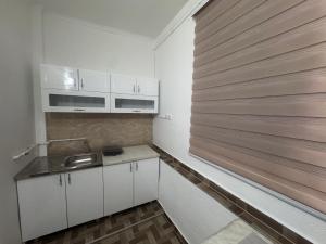 a kitchen with white cabinets and a wooden wall at Apartman Kaljević in Prijepolje