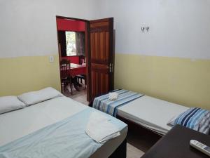 two beds in a room with a table and a room with a chair at Quartos em Alter do Chão in Santarém +1 photo