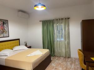 ein Schlafzimmer mit einem Bett und einem grünen Vorhang in der Unterkunft Hotel Vila C plus plus in Berat