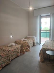a room with three beds and a table and a window at Bergamo Rooms 1 & 2 in Bergamo