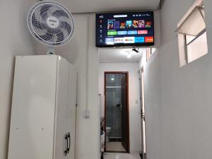 a bathroom with a fan and a tv on the wall at Kitnet slim no Centro in Vitória da Conquista