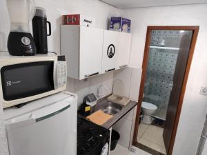 a small kitchen with a microwave and a sink at Kitnet slim no Centro in Vitória da Conquista