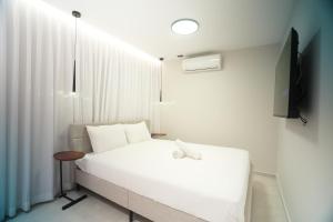 a bedroom with a white bed and a television at alma in Eilat