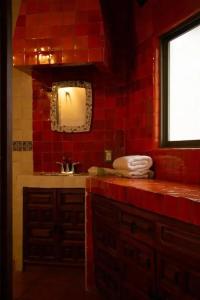 Un baño de azulejos rojos con lavabo y espejo. en Hotel María Emilia, en Cuernavaca