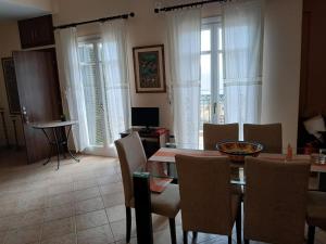 a dining room with a table and chairs and windows at Sunset Balcony in Kyparissia