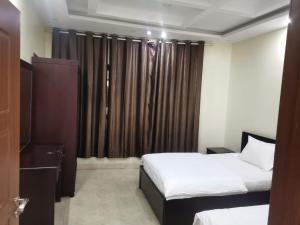 a bedroom with two beds and a window with curtains at شقق مفروشه قارا in Qārā