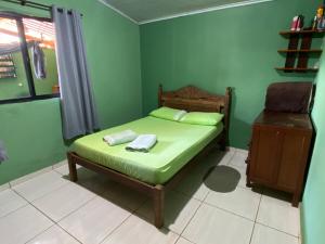 a green bedroom with a bed and a chair at Aconchego ao pé da serra in São Roque de Minas