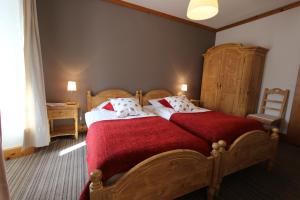 - une chambre avec un grand lit et une couverture rouge dans l'établissement Hôtel de Ville, à Château-d'Oex