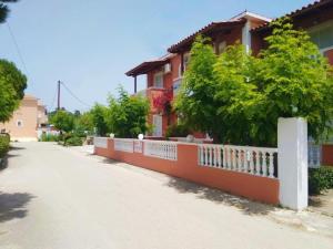 a house with a white fence next to a street at Panagiotis Studios 2 in Laganas