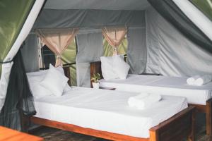 two beds in a tent with white sheets and pillows at Radiance Ella Urban Camping in Ella